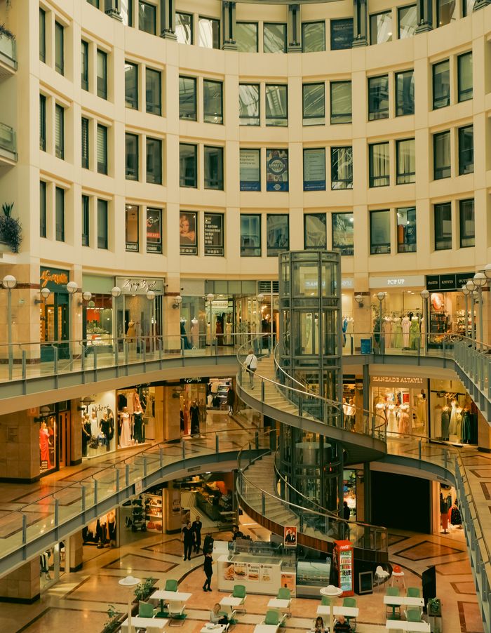 Spacious interior of a modern shopping mall in Ankara featuring a central glass elevator and atrium design.