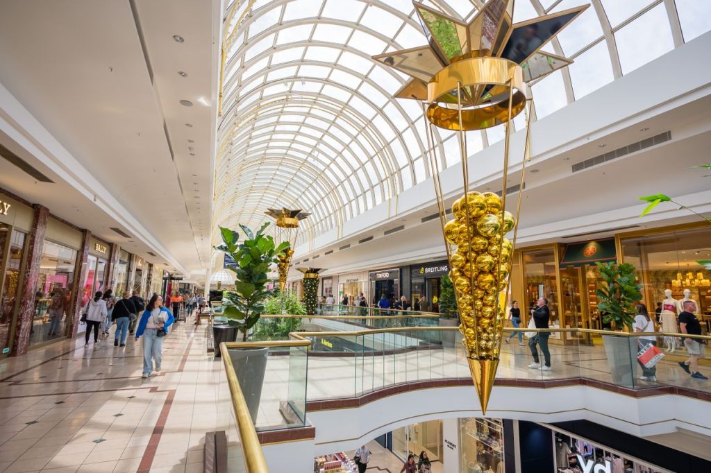 Vibrant shopping mall interior featuring holiday decorations and shoppers enjoying the seasonal ambiance.