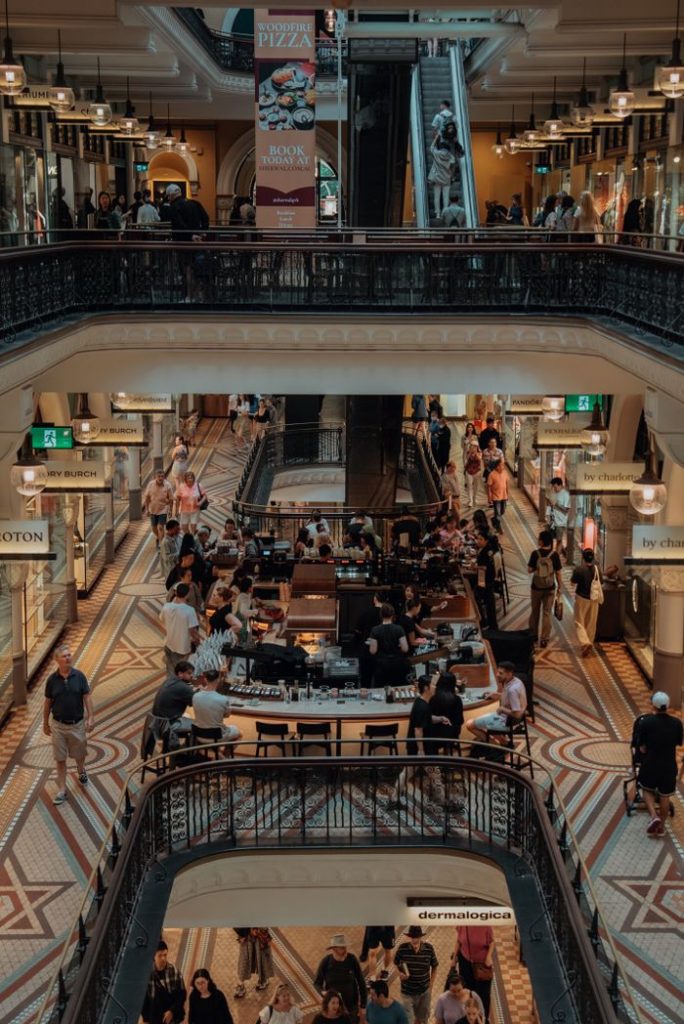 View of a busy shopping arcade in Sydney with shops, escalators, and people enjoying their day.